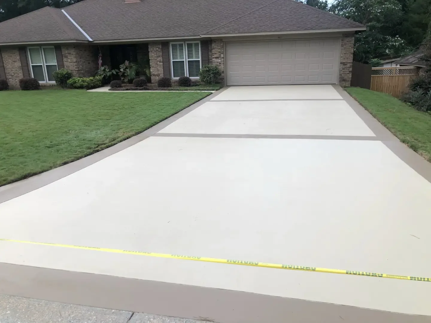 Newly finished plain concrete driveway with a broom texture running up to a two-car garage