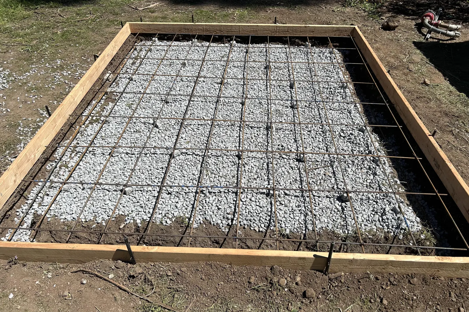 Wood forms and a rebar grid set over a crushed stone base before a concrete slab pour