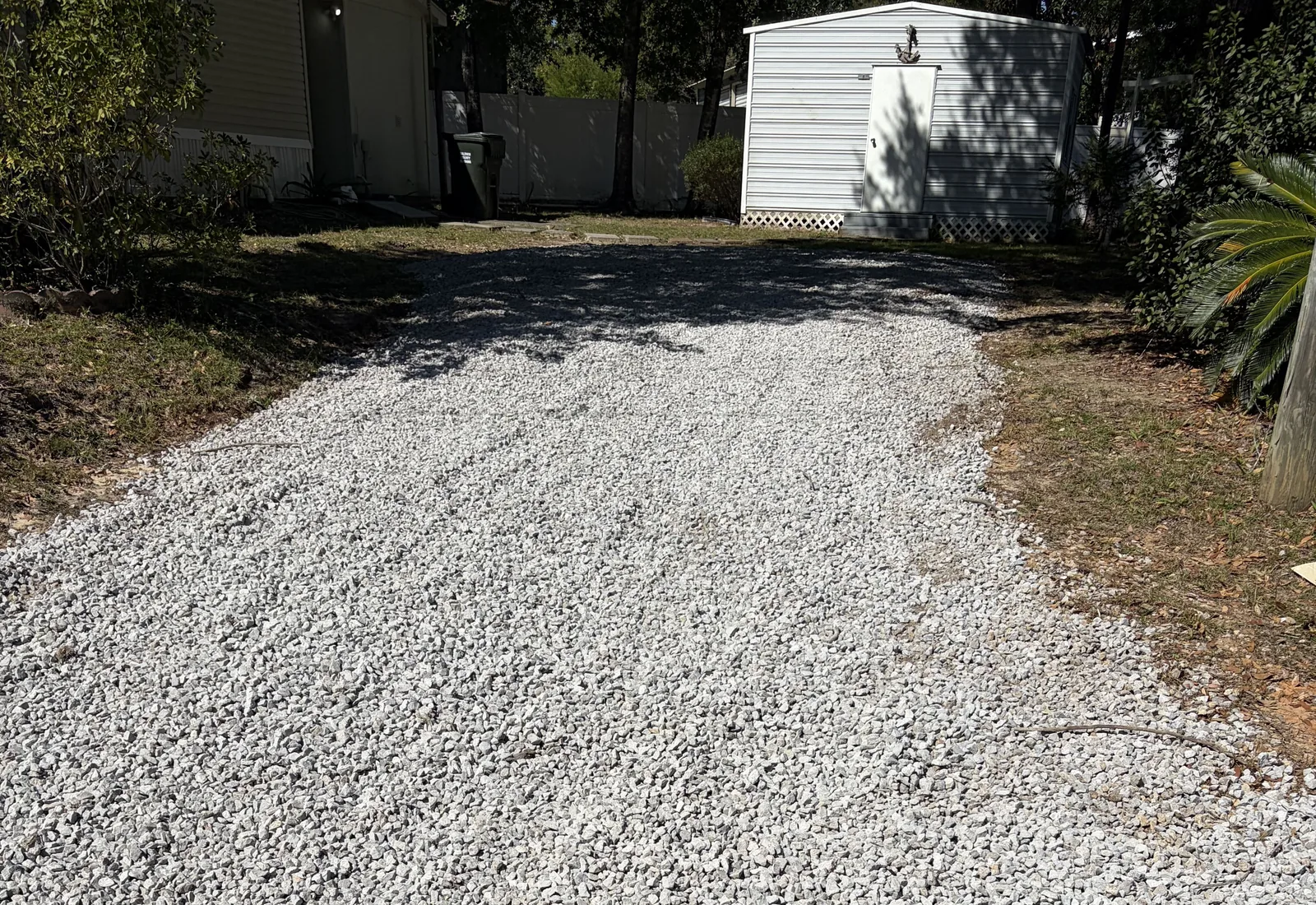 Fresh crushed stone spread edge to edge on a rehabbed gravel driveway, a storage shed at the far end